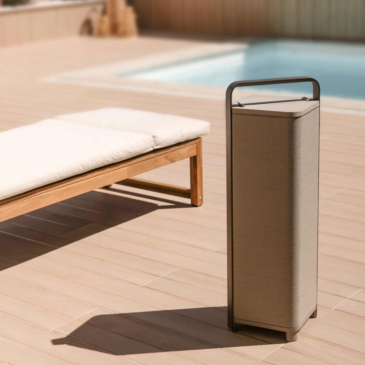 ESCAPE P9 mobiler Design-Lautsprecher in eleganter Korboptik – platziert auf sonniger Terrasse neben Poolliege.